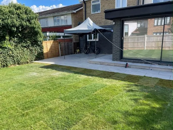 After: the same garden with large format grey paving laid off the extension and new turf run right up to the edge