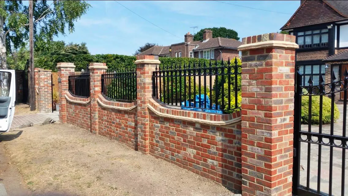 Reclaimed brick boundary wall with piers, shaped stone coping and black iron railings