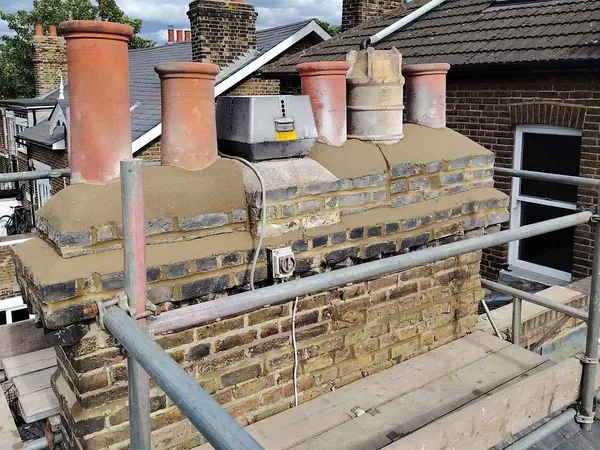After: the same stack with the flaunching recast, the brickwork repointed and the pots back on