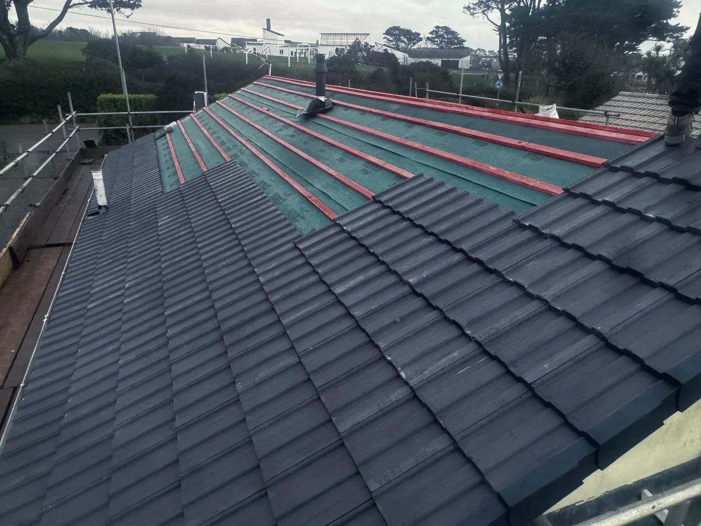 Half tiled roof showing green breathable membrane and treated battens underneath