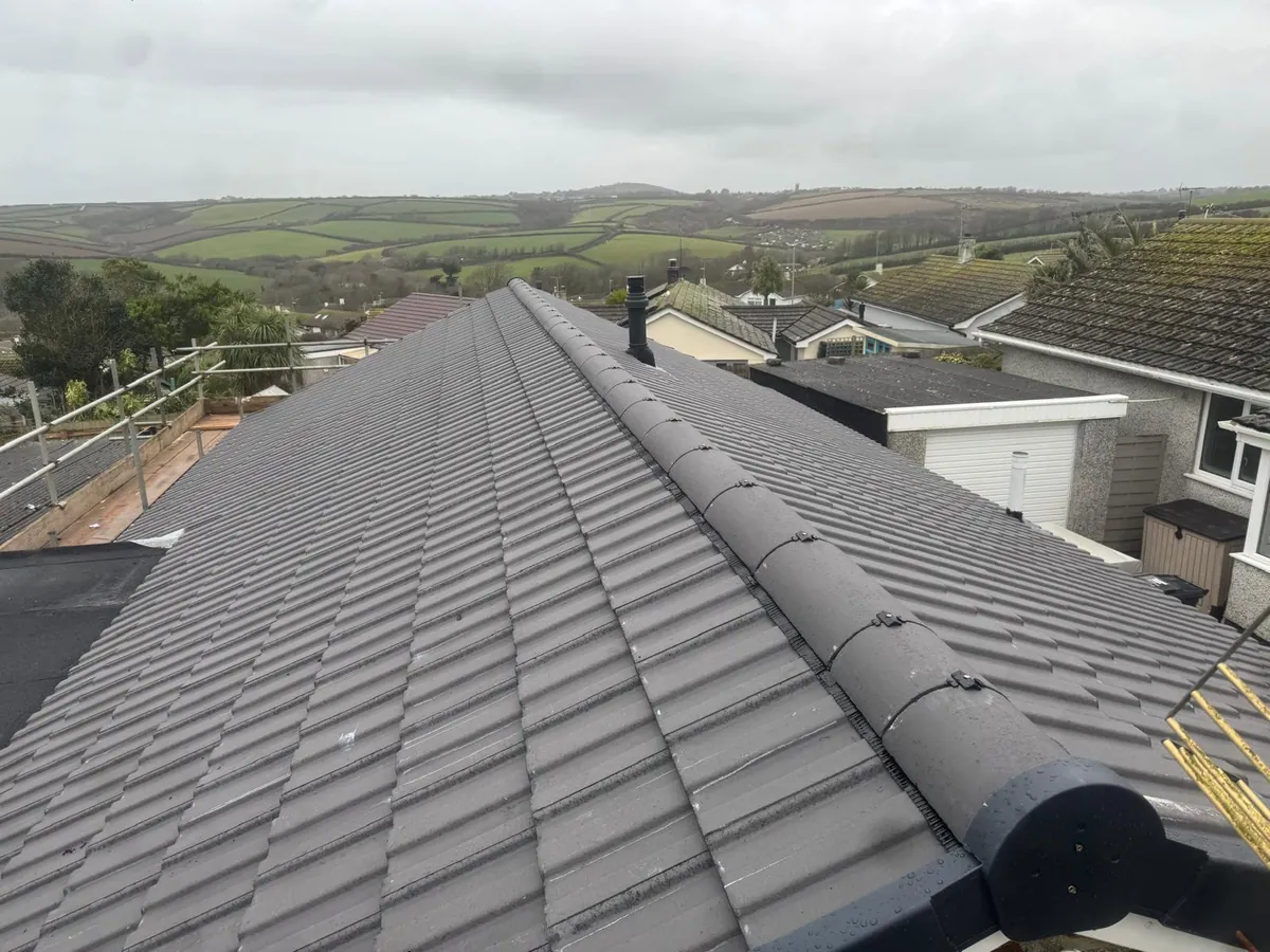 New grey tiled roof plane with a dry-fixed ridge, finished by Southridge