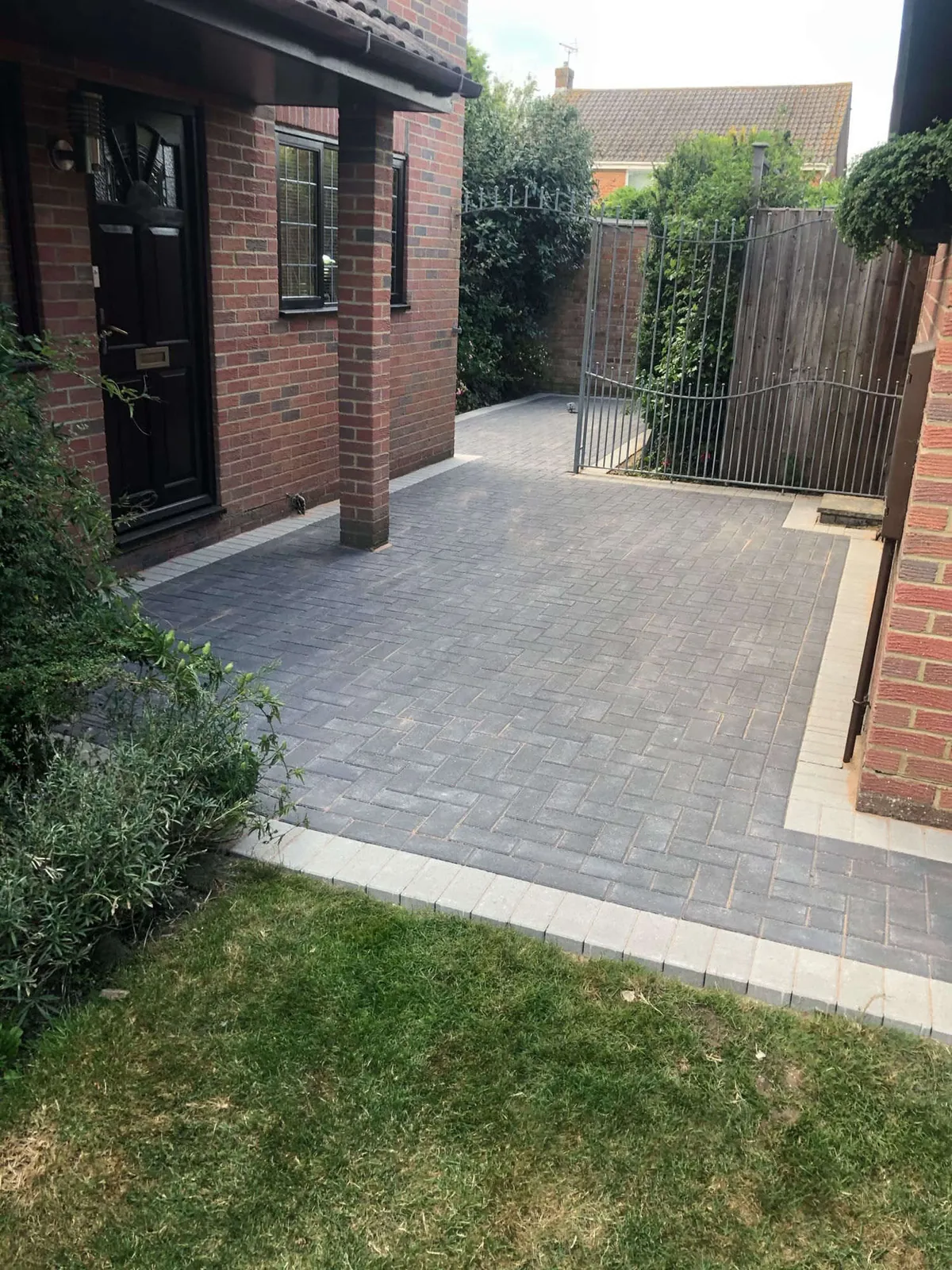 Charcoal block paved driveway and side access at a red brick house