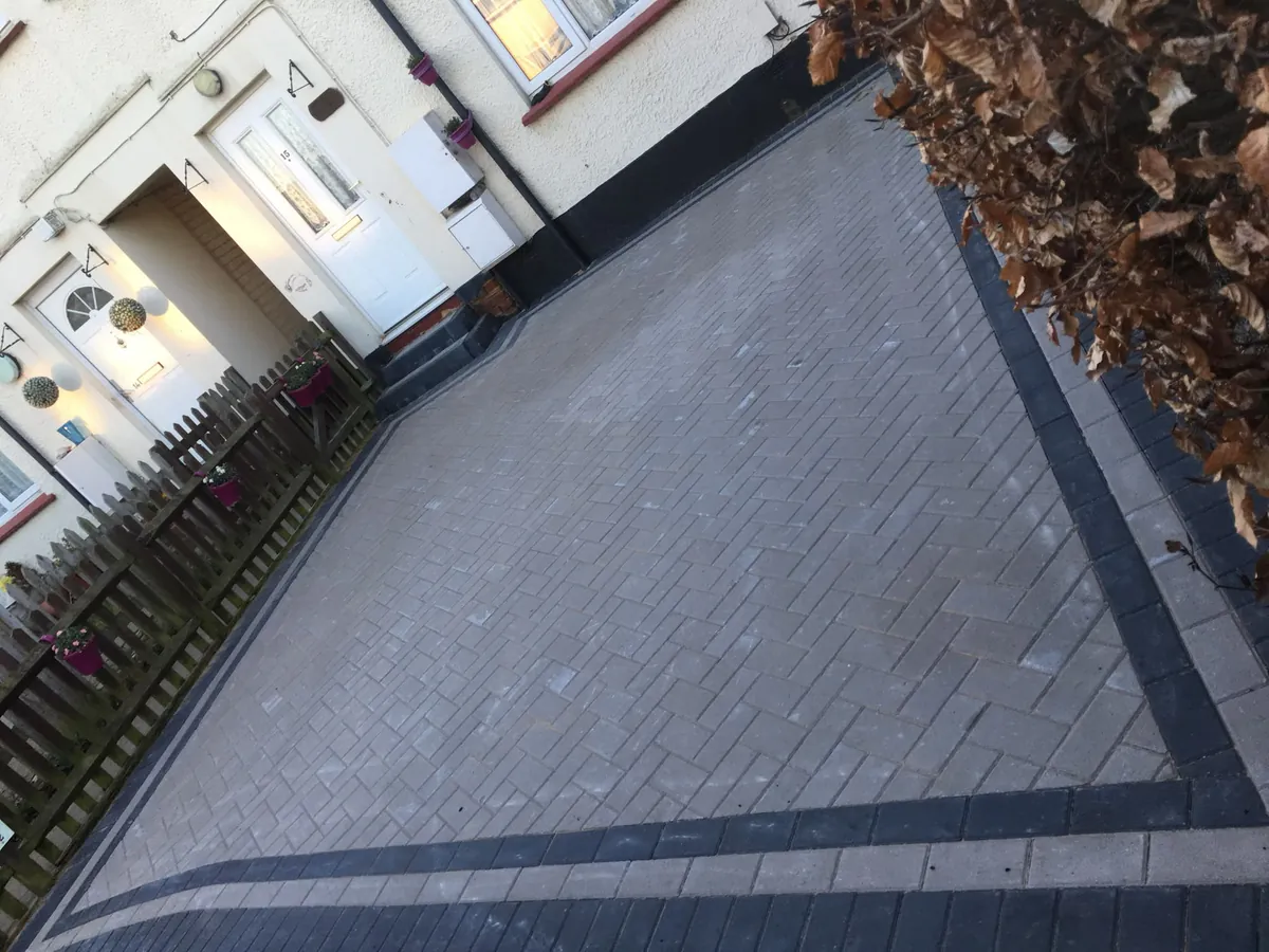 Block paved driveway with a dark contrasting double border alongside a house