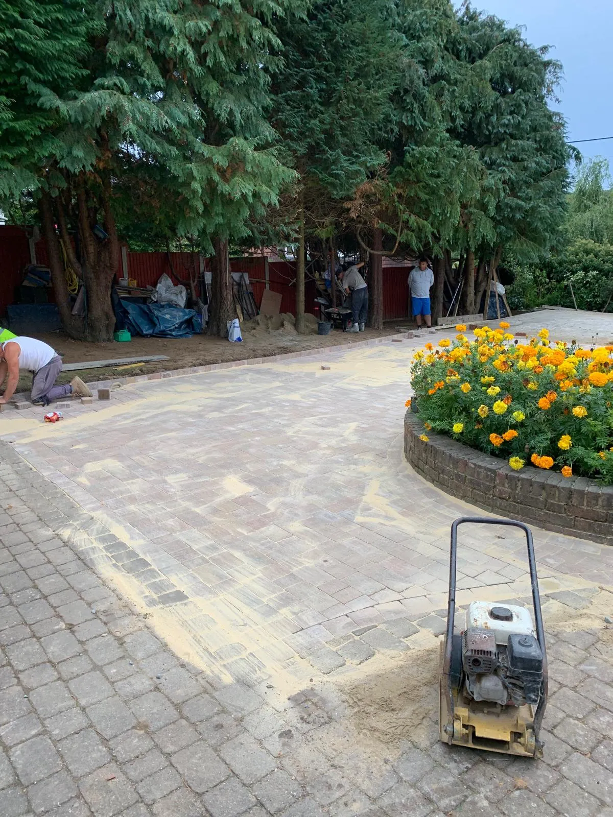 Plate compactor and kiln dried sand being worked into a new block paved driveway