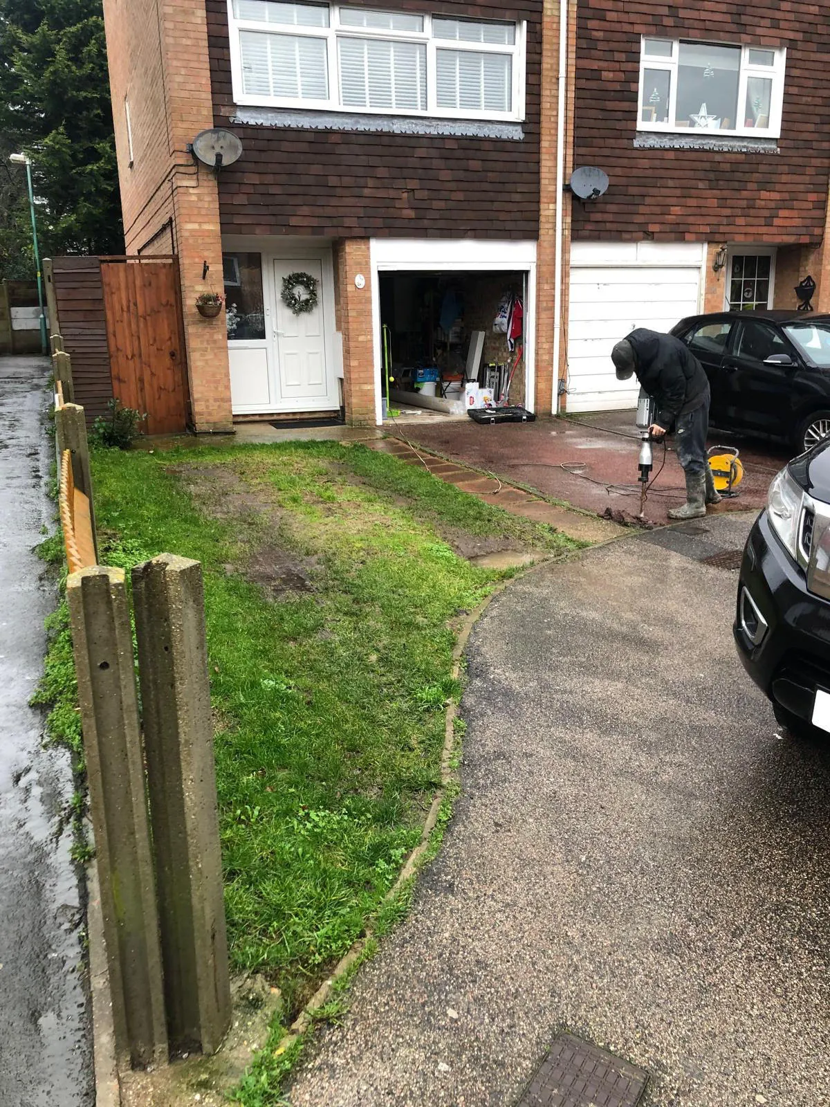 Before: mossy front lawn being broken out on a wet day, garage open behind