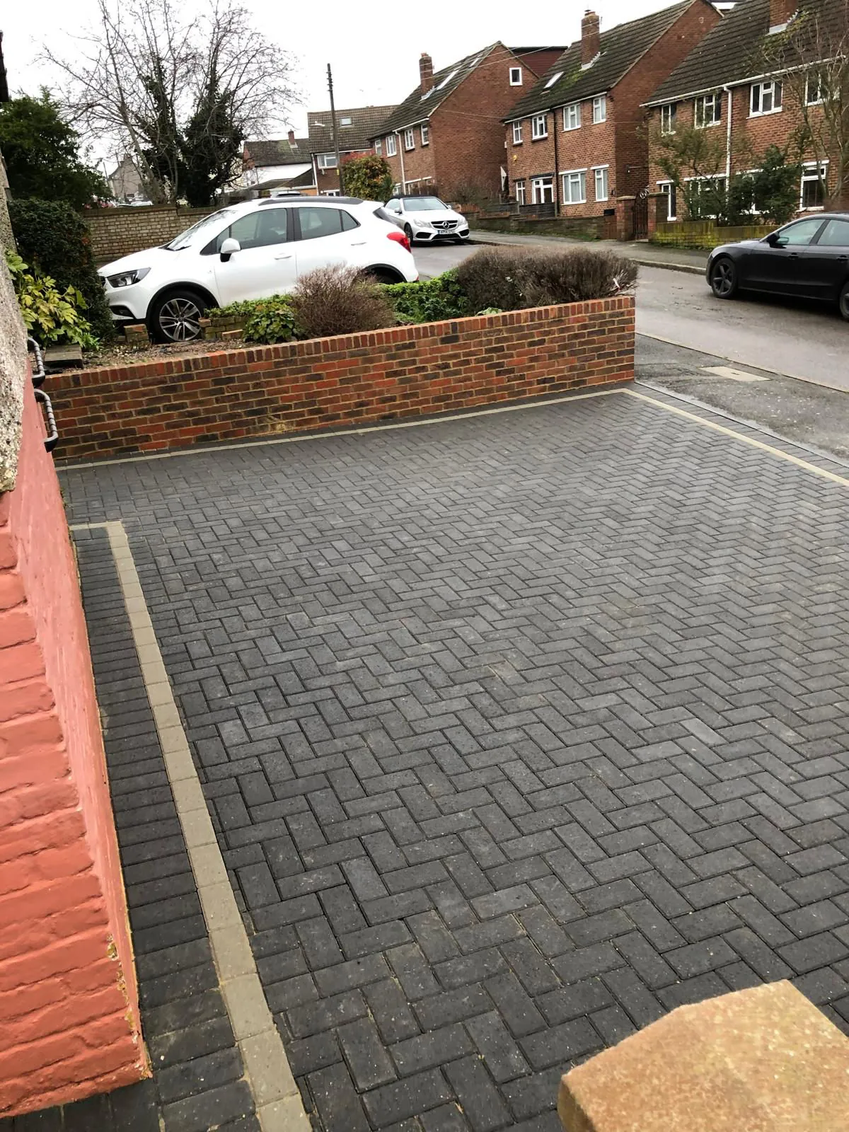 Herringbone block paved driveway with a new brick retaining wall