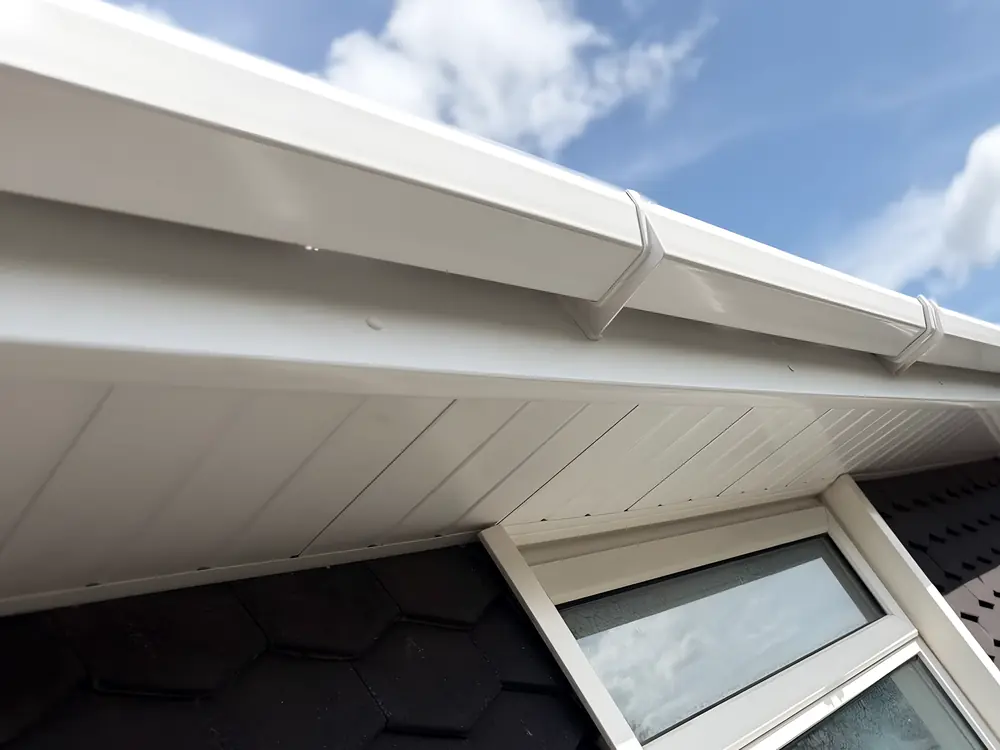 New white uPVC soffit, fascia and guttering seen from below, with blue sky beyond